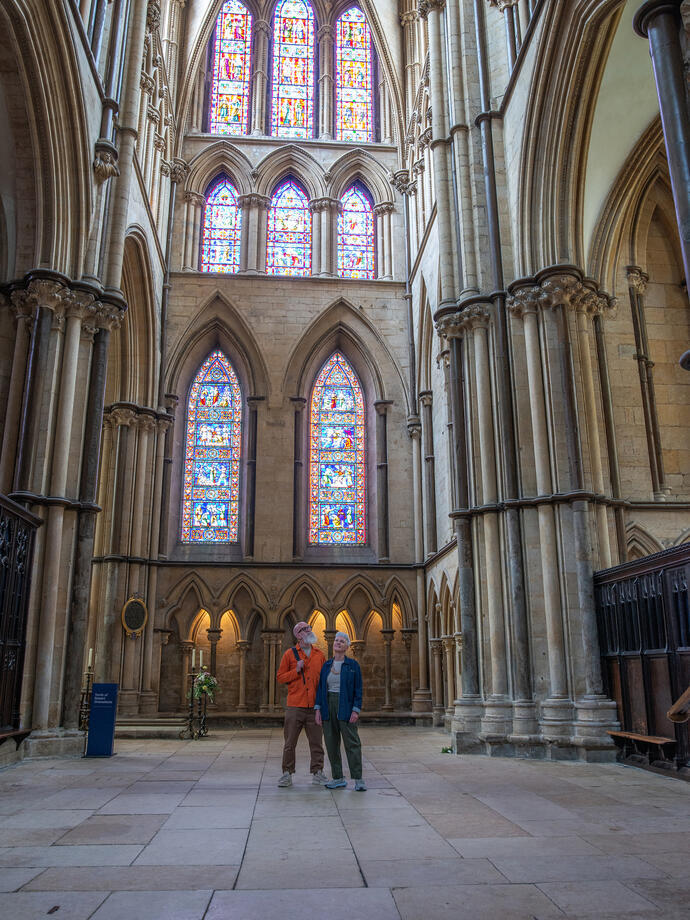 A man and a woman standing together looking up at the stained glass windows of a Cathedral