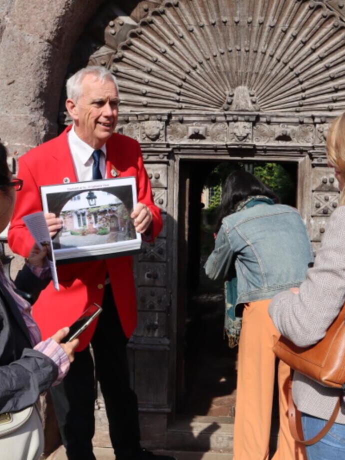 A tour guide in a red blazer leading a tour group around the centre of city