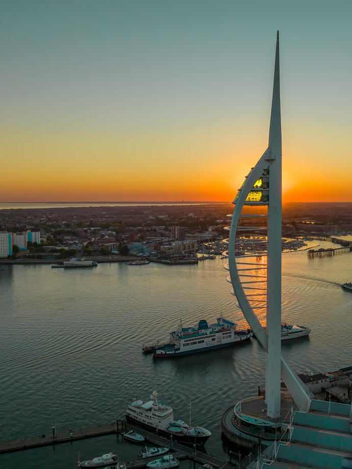 A modern tower next to the ocean at sunset