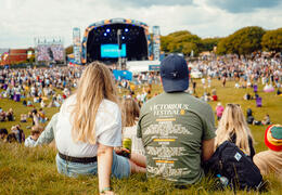 People sitting down and watching the stage at a music festival
