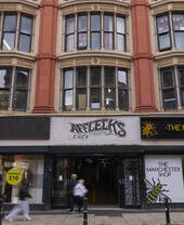 Esterno di Afflecks e The Manchester Shop con persone che camminano sul marciapiede nel centro di Manchester.
