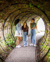 Tres mujeres dentro de un túnel de plantas en un jardín