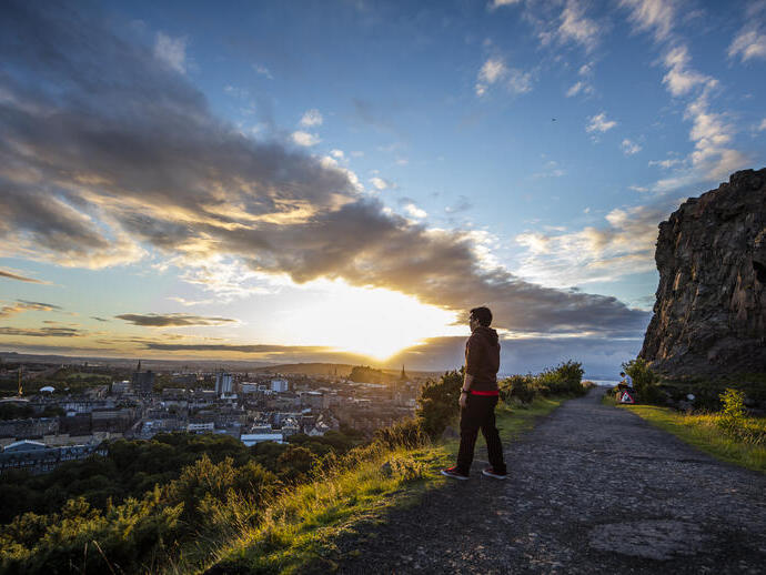 Uomo che ammira la vista panoramica di Edimburgo dalla cima dell'Arthur's Seat