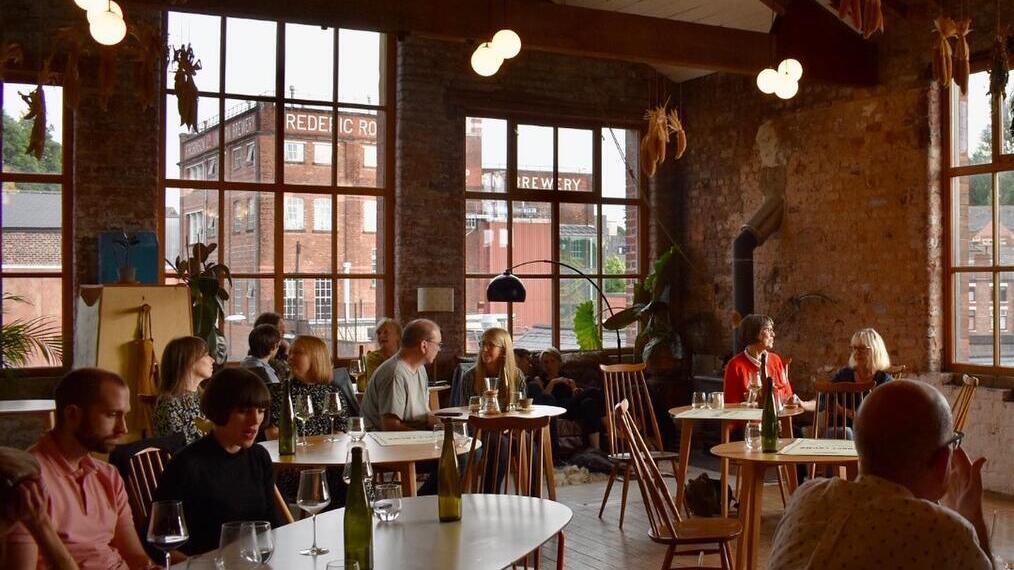 People sitting down enjoying a glass of wine at Where The Light Gets In restaurant