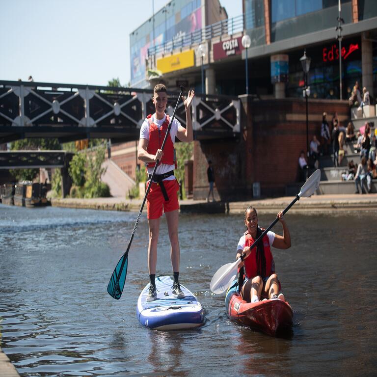 Two men kayaking on canal through central Birmingham