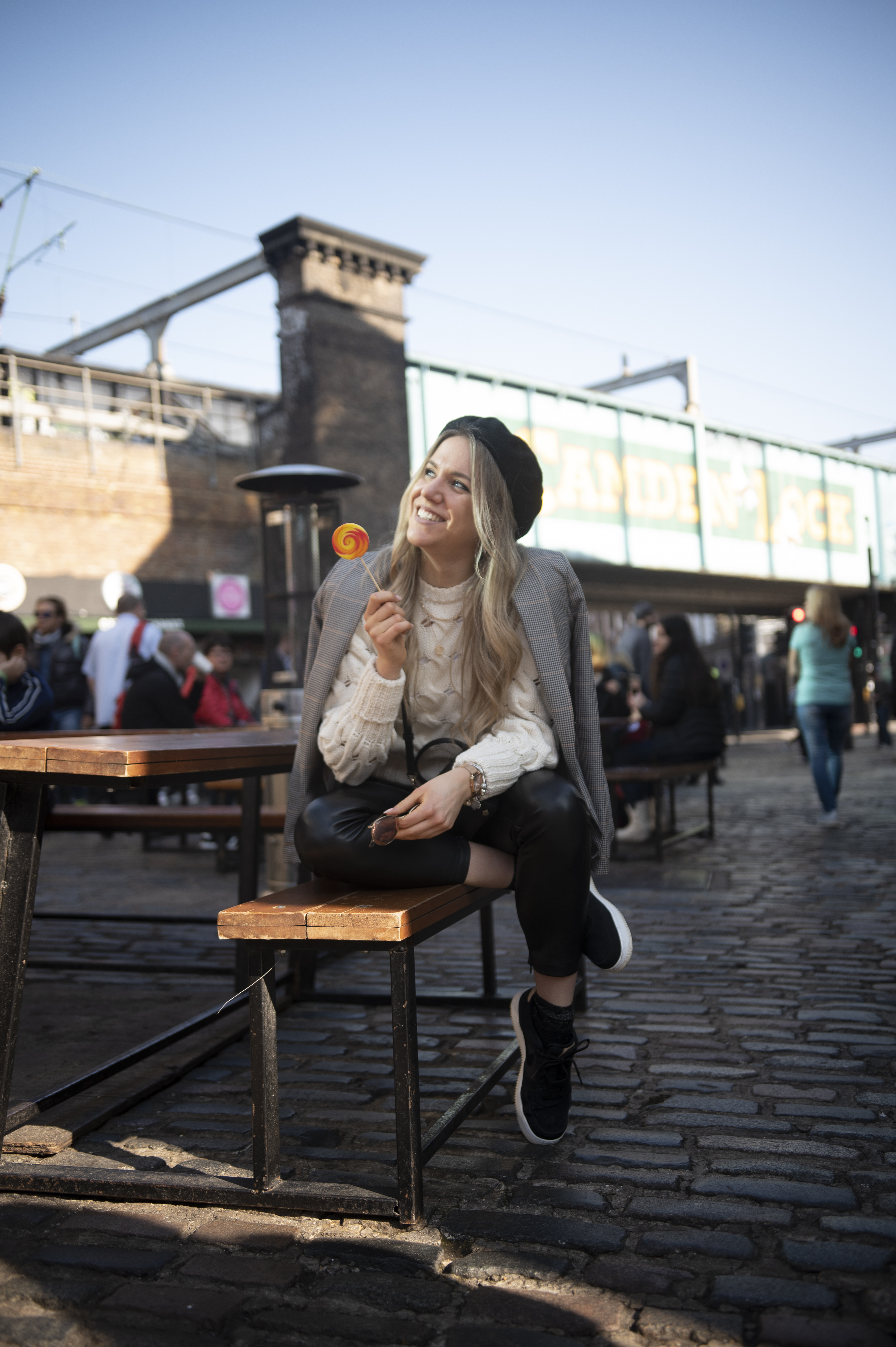 A woman sitting on a bench smiling and holding a lollipop