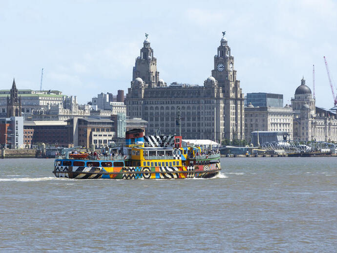 A view to a ferry on a river in front of the Liver building
