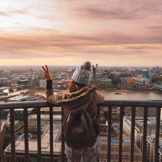 Woman on a balcony at the top of a high building looking over a city