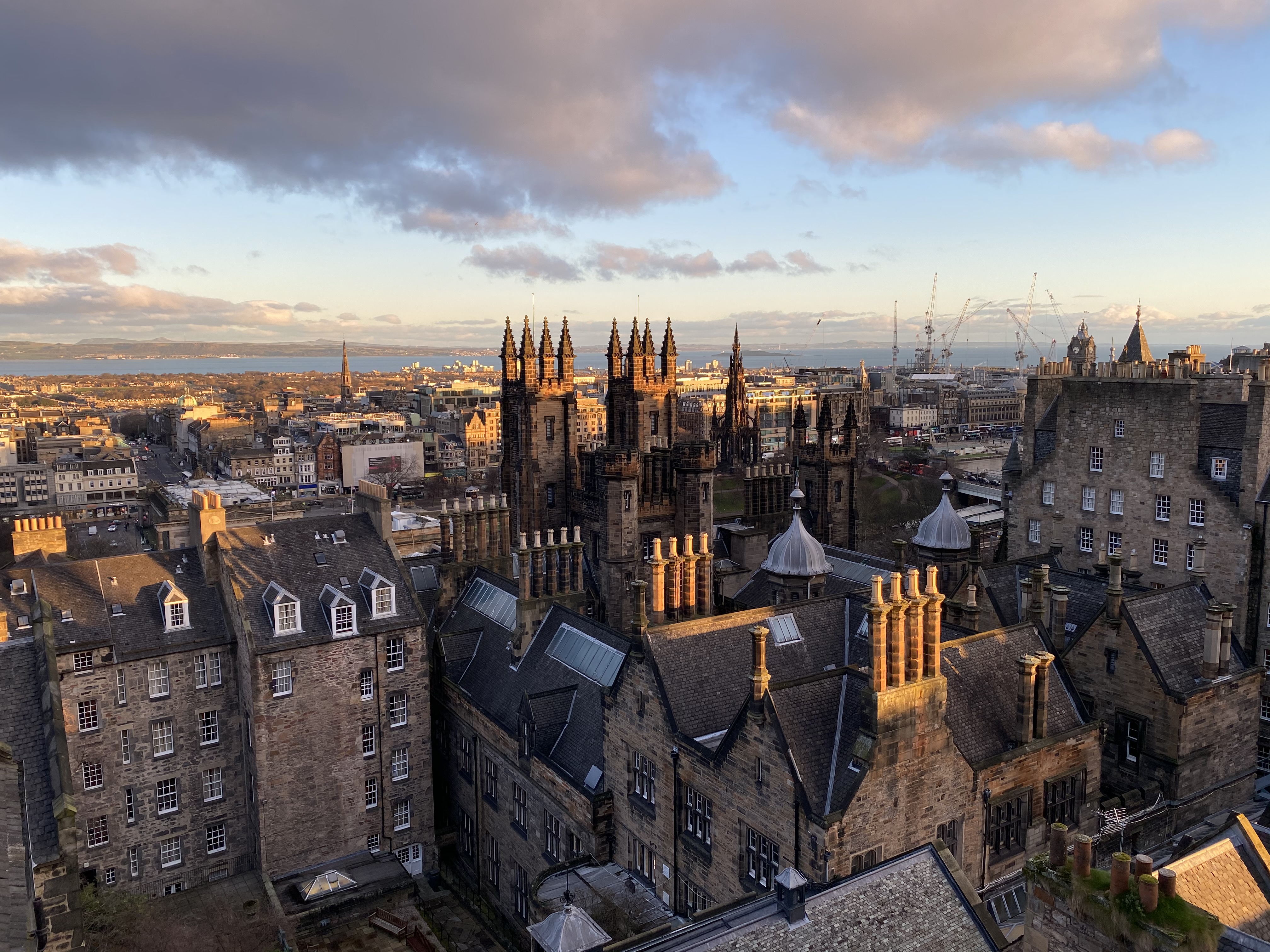 High view of rooftops of Edinburgh with sea beyond as seen from Camera Obscura World of Illusions attraction