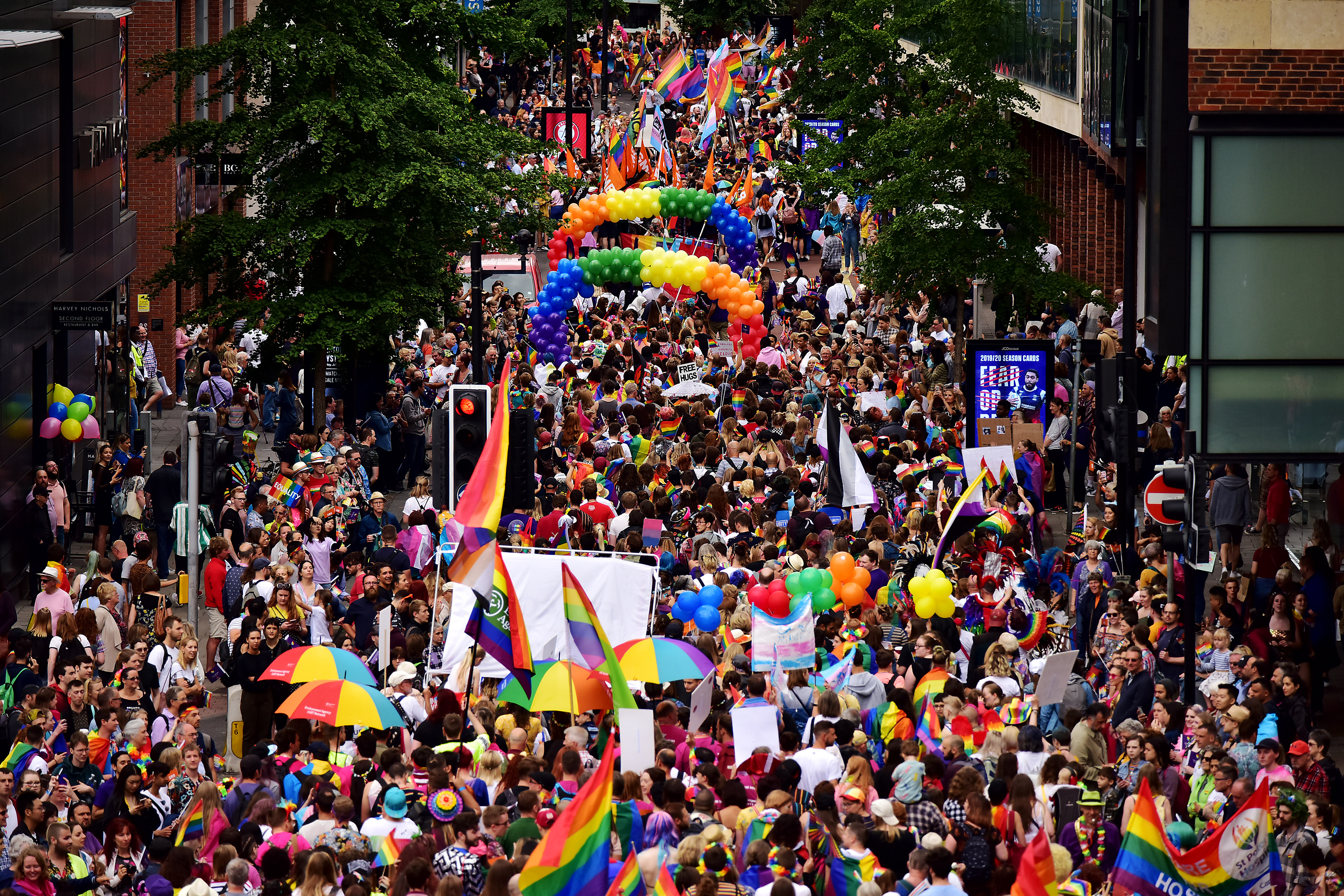 Menigte die meeloopt in een parade, met regenboogvlaggen, paraplu's en ballonnen