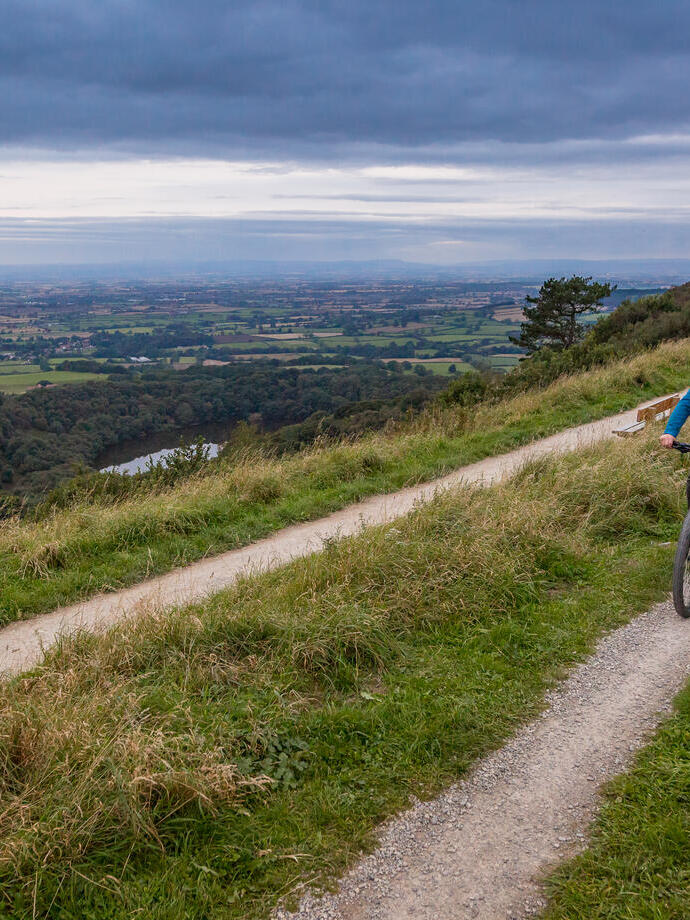Man and woman riding bikes along a path on a ridge