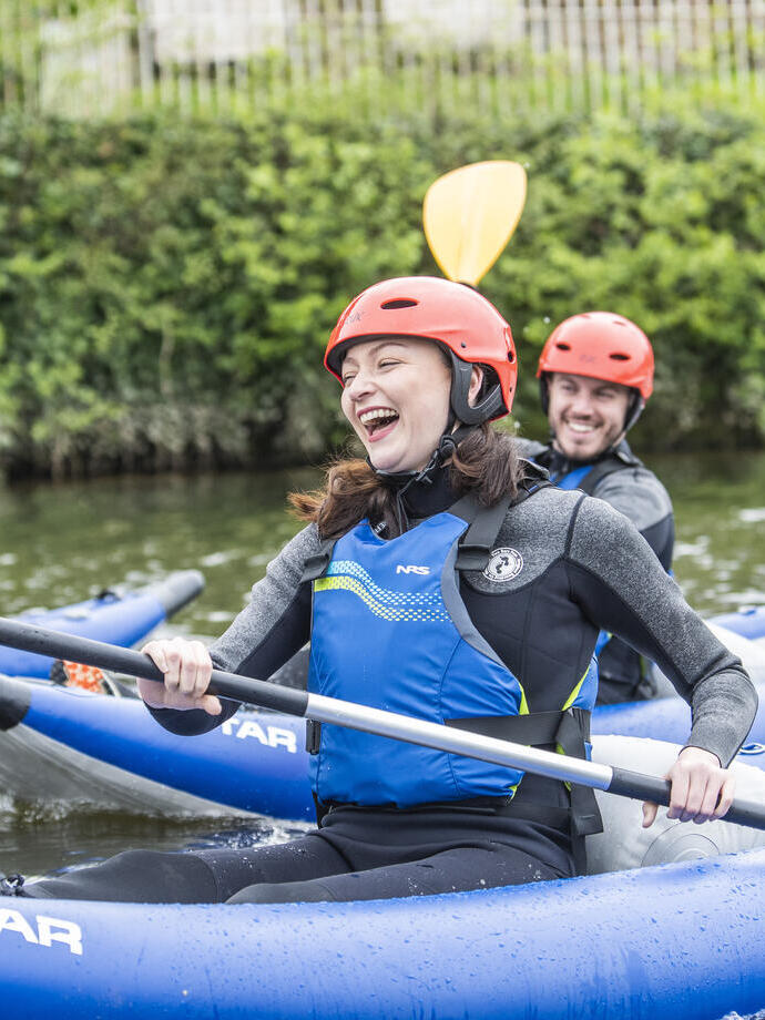 People smiling and laughing while kayaking down a river in Chester