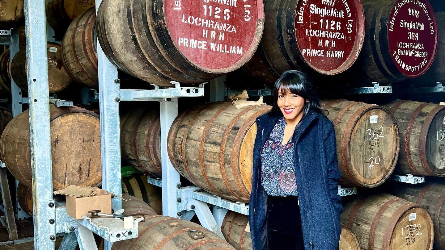 Una signora in piedi accanto a botti di whisky alla Lochranza Distillery, Isola di Arran, Scozia