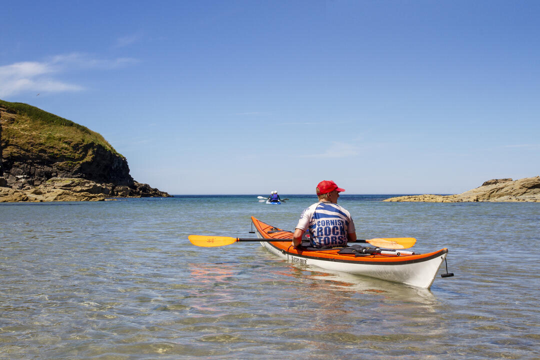A close up of someone kayaking through the sea off the coast of Cornwall