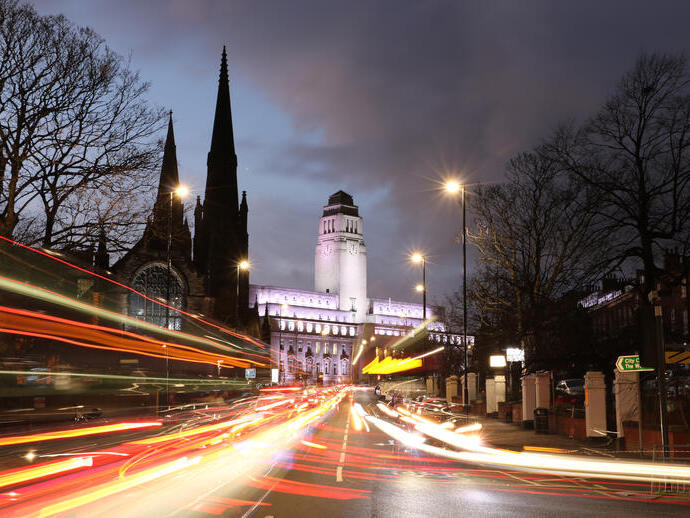 A view of a university taken from the street at night.