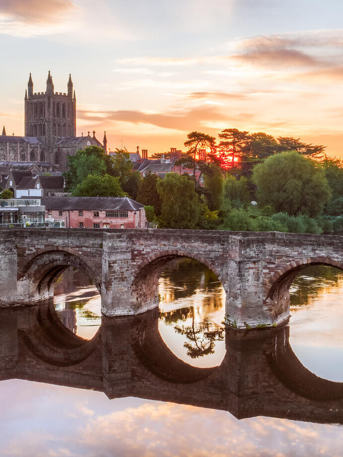 Ponte romano su un fiume con una cattedrale sullo sfondo all'alba