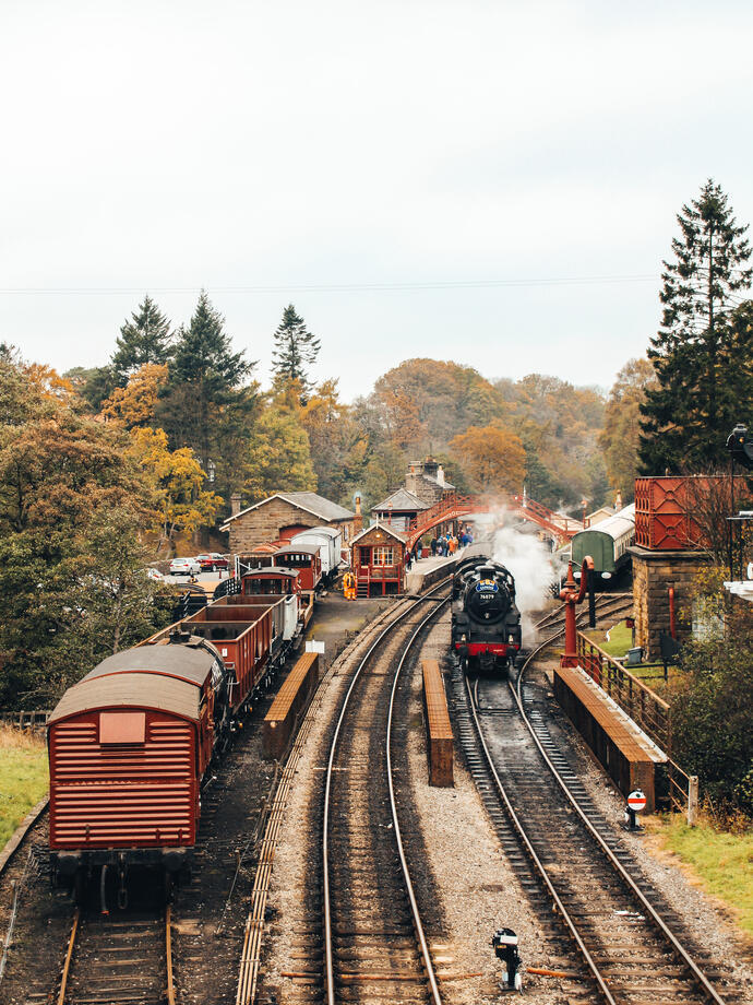 Steam train on train tracks and old-fashioned carriages at Goathland Railway Station