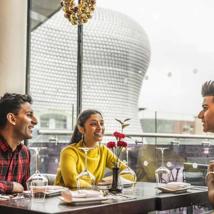 Tres jóvenes sentados en una mesa con vistas panorámicas