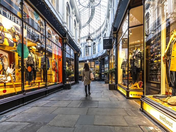 Woman walking through an arcade between shops, lit up from inside