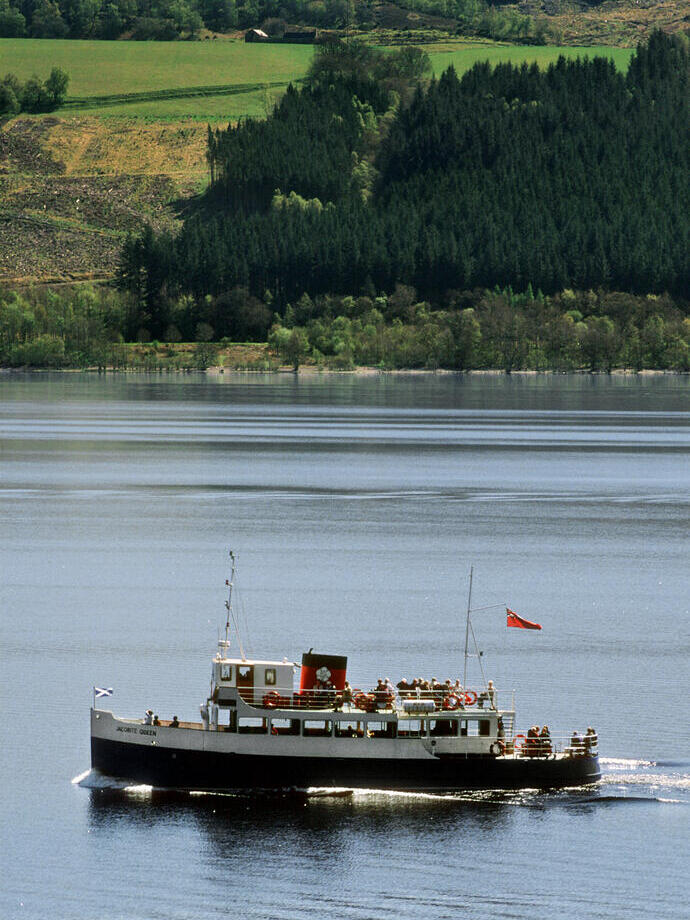 Bateau de plaisance traditionnel bleu et blanc avec une cheminée rouge et noire transportant des visiteurs sur un lac.