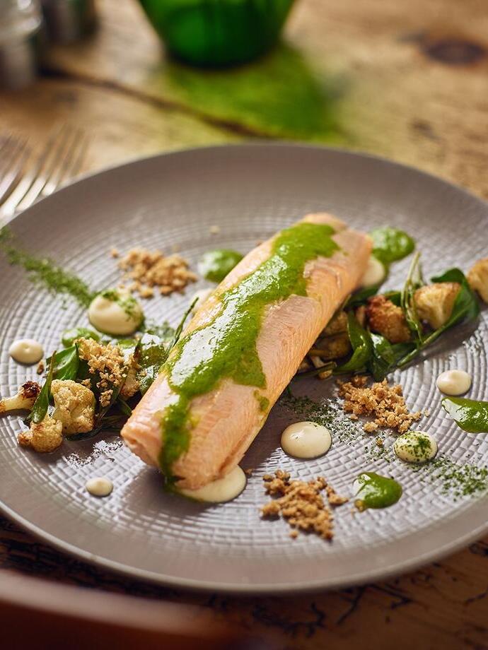 River trout decoratively served with a green and cream garnish at an upmarket gastropub in the countryside.