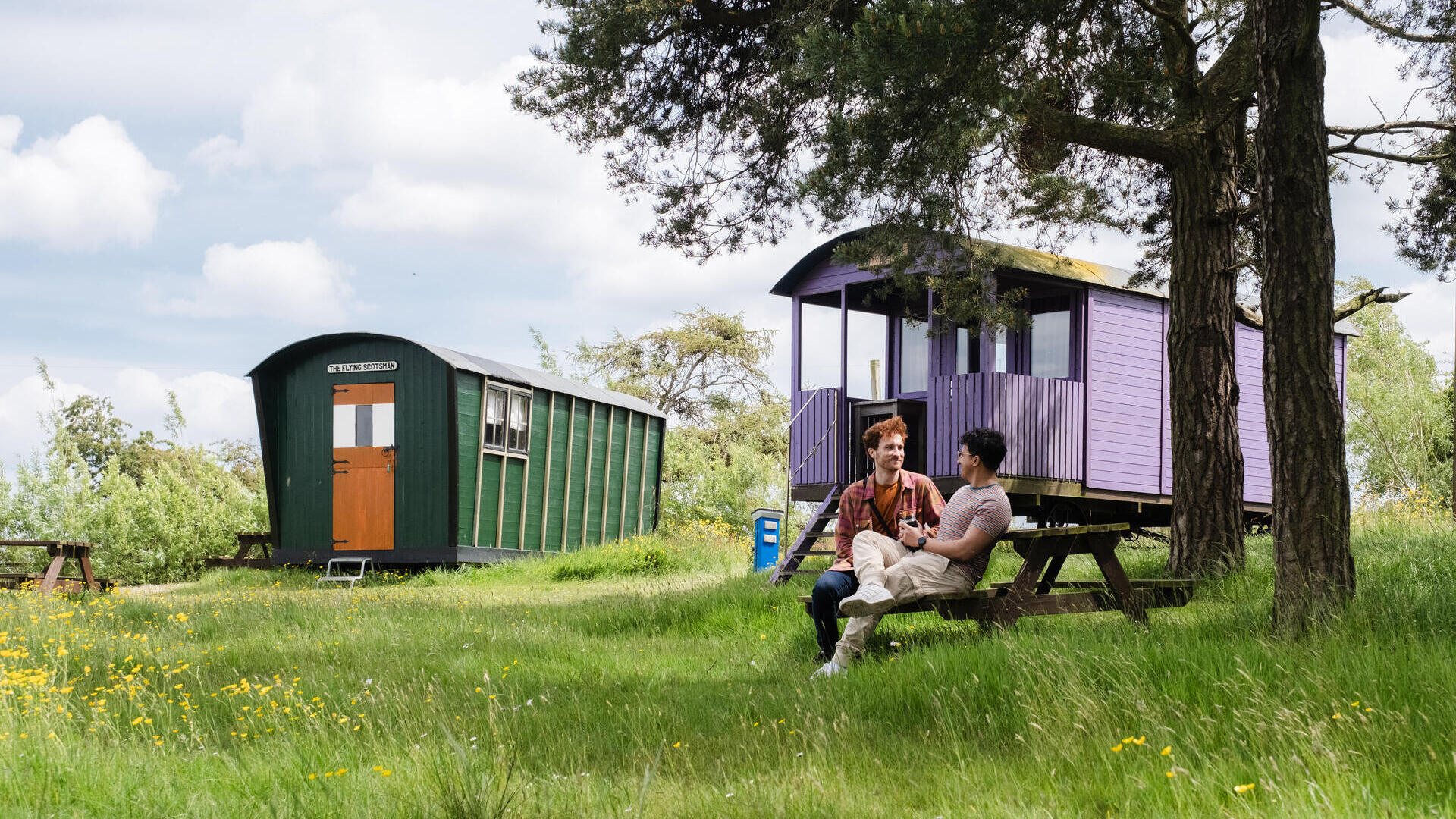 Zwei Männer sitzen vor einer Schäferhütte auf dem Land