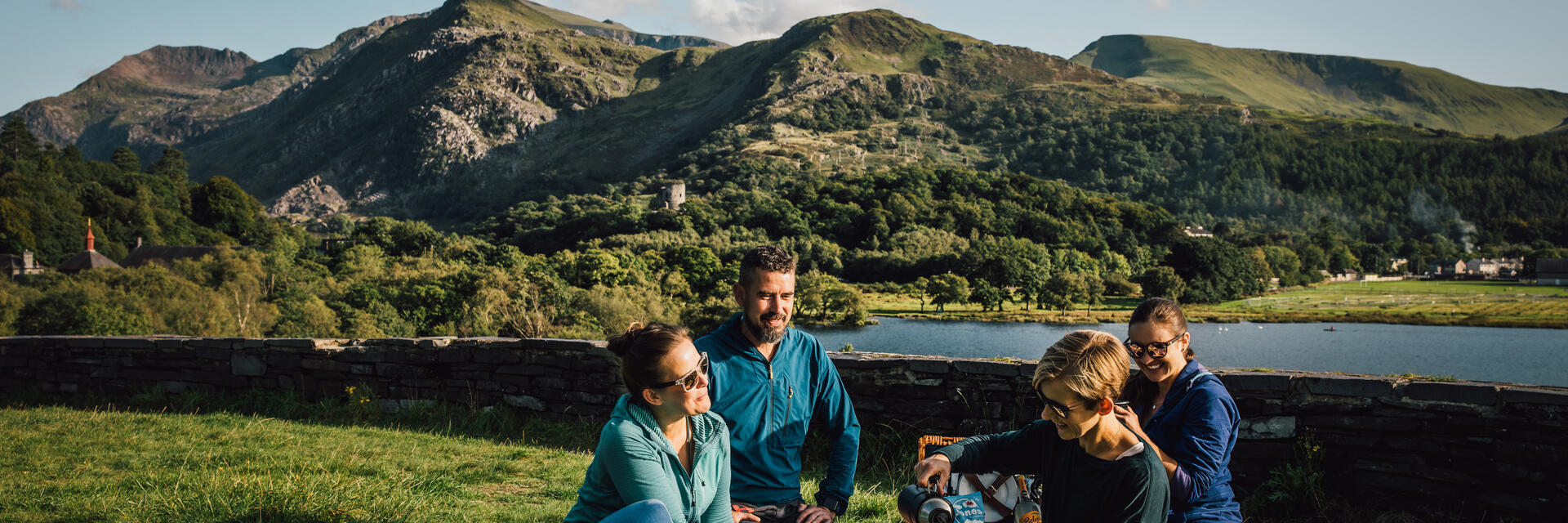 Des amis pique-niquent dans une prairie au bord d'un lac glaciaire.
