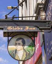 A sign for a traditional British pub that reads 'Globe Inn', with a portrait of a man.