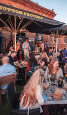 People sat at outside tables drinking at a bar in the evening