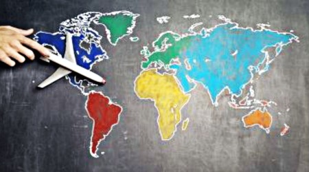 Hand pushing plane model over image of world countries