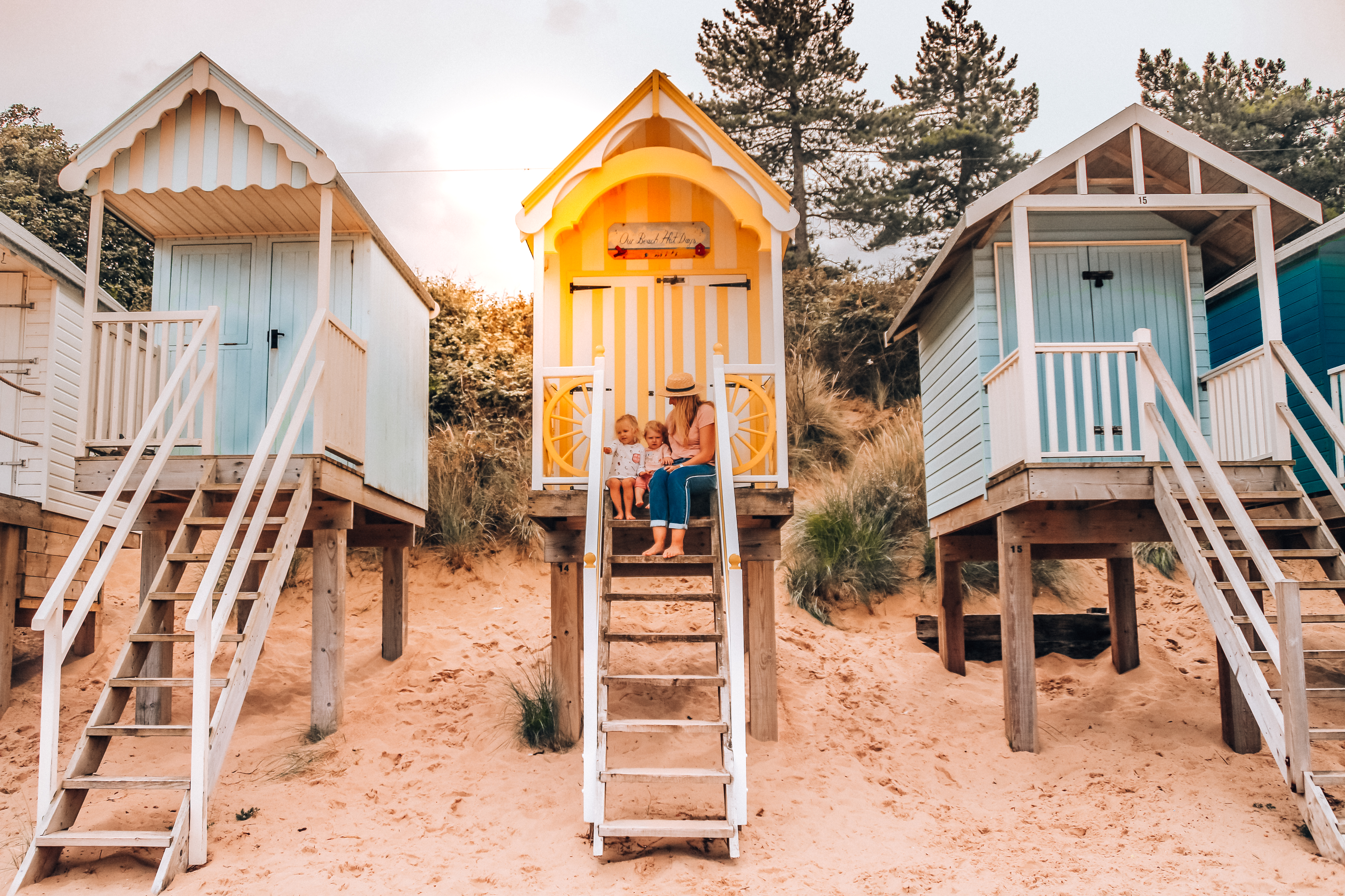 امرأة وأطفال يجلسون على أعلى درجة من كوخ شاطئي