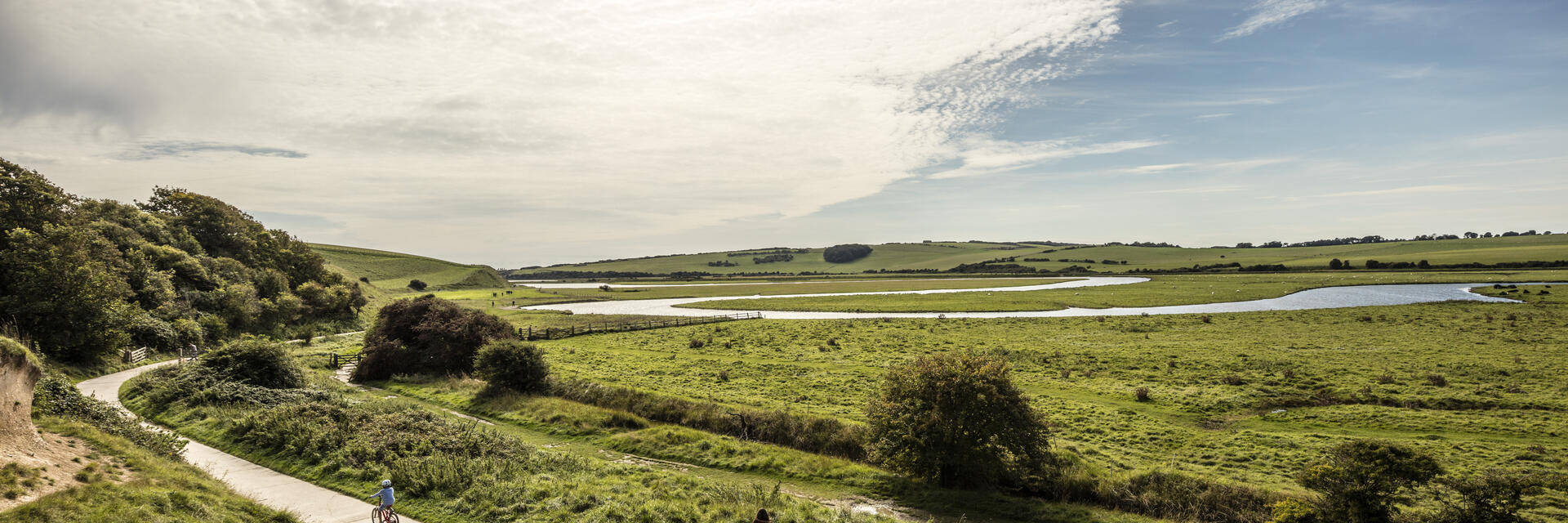 Eine Familie, die auf einem Weg durch die weite englische Graslandschaft Rad fährt.