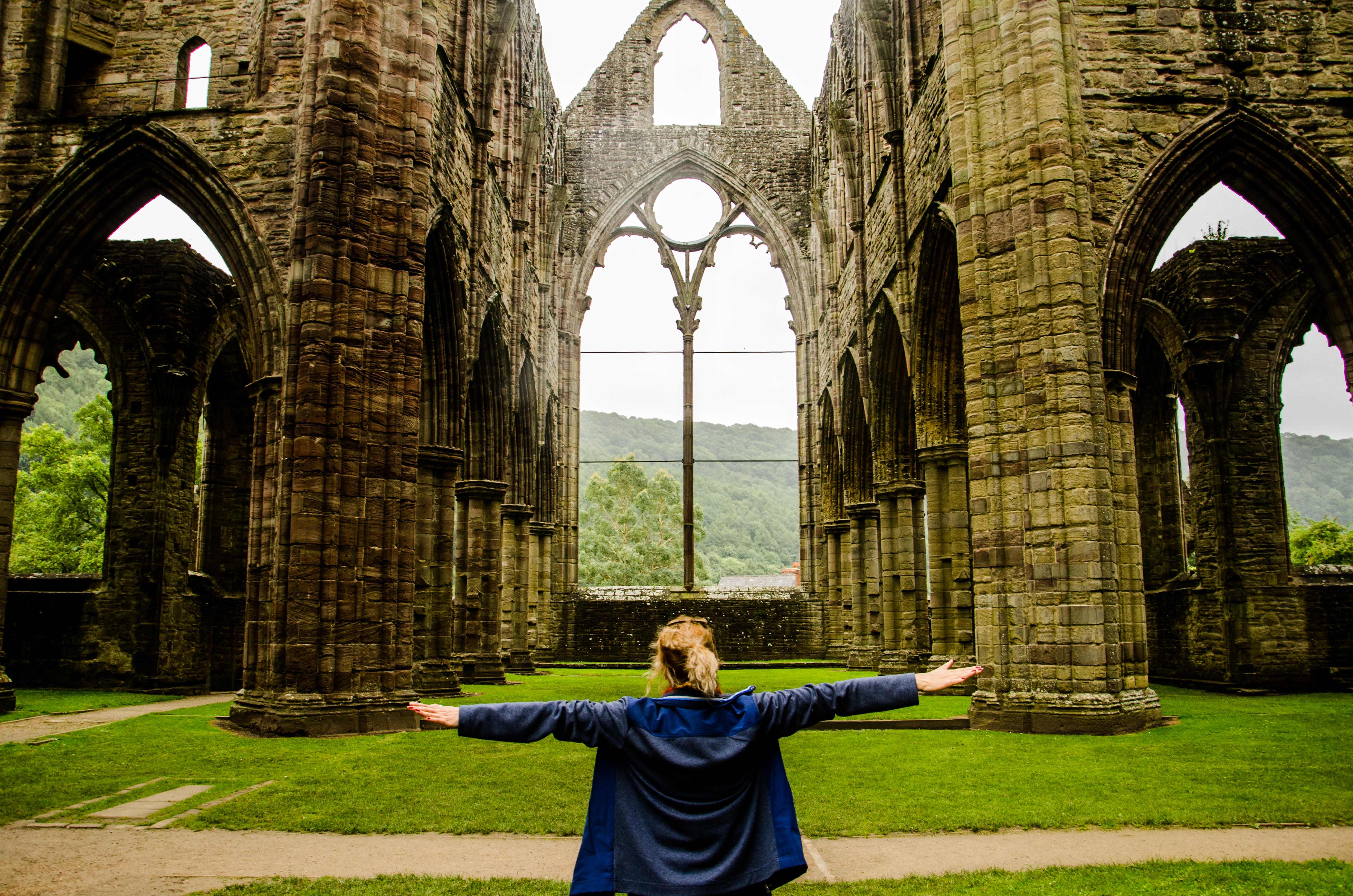 A woman with arms out stretched inside a vacant crumbling church