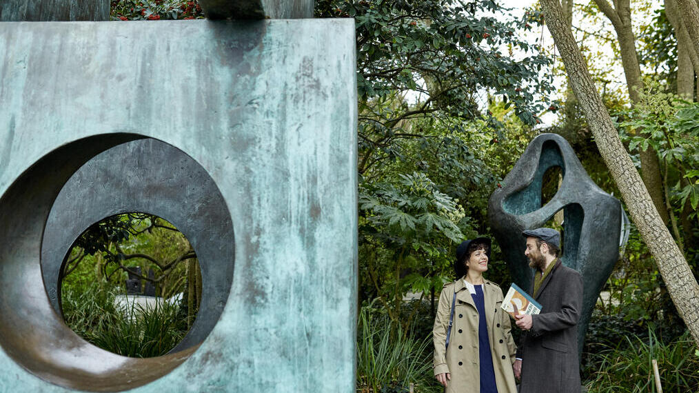 Couple standing next to bronze sculptures in a garden