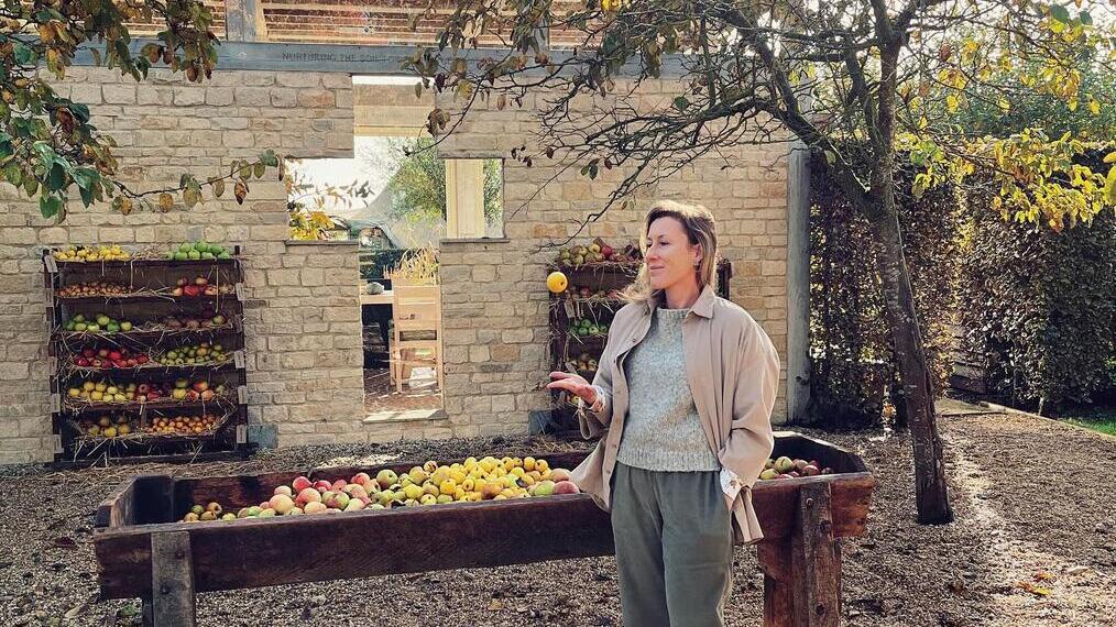 Mujer junto a un cubo de manzanas, granja ecológica Dalesford