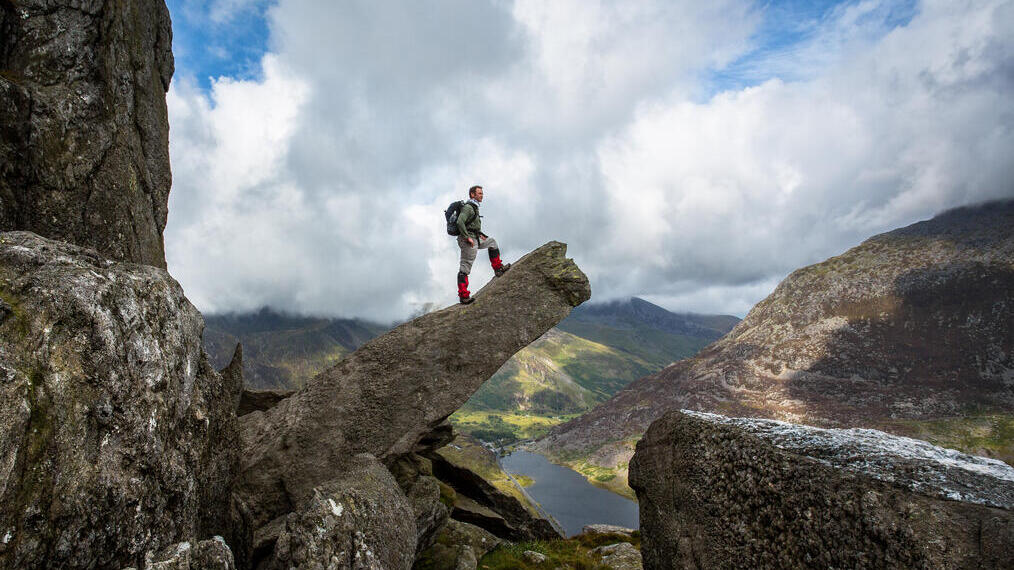 Un homme debout sur un rocher en saillie, admirant la vue