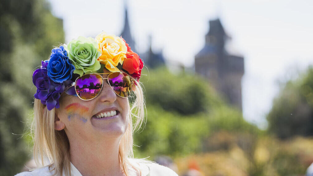 Mujer con flores de colores vivos en el pelo y pintura facial sonriendo