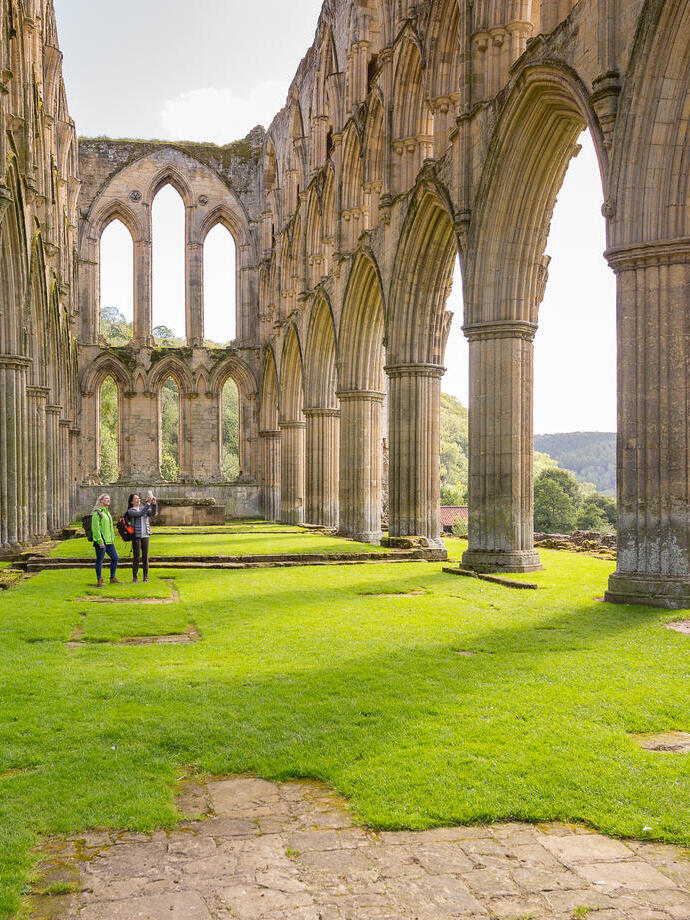 Two female friends in the central nave of a ruined abbey in the sunshine