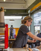 Une femme servant des boissons à un stand du marché de Norwich