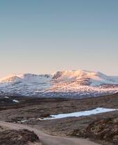 A rugged road leading through the valley to snow covered mountains in the distance