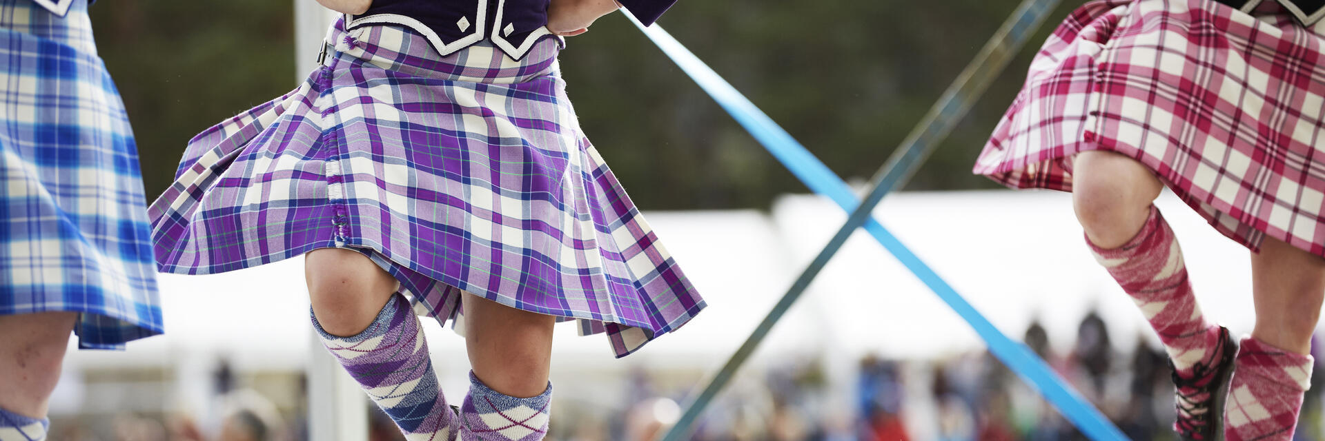 Drei Mädchen in Kilts tanzen schottische Tänze auf der Bühne