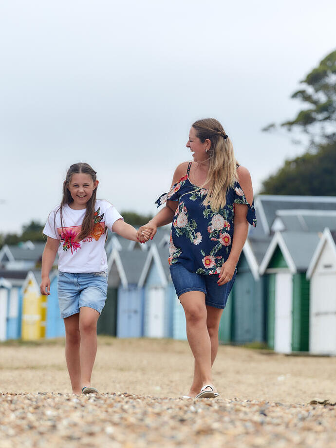 Family walking on a beach in front of beach huts