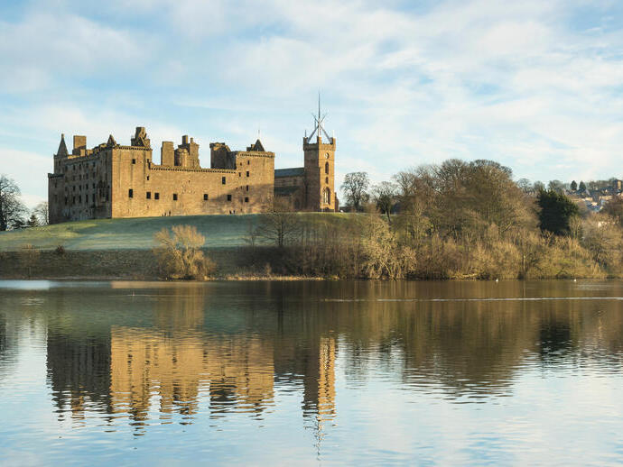Exterior de una iglesia y un castillo parcialmente en ruinas cerca de una ciudad con vistas a un lago con cisnes en invierno.