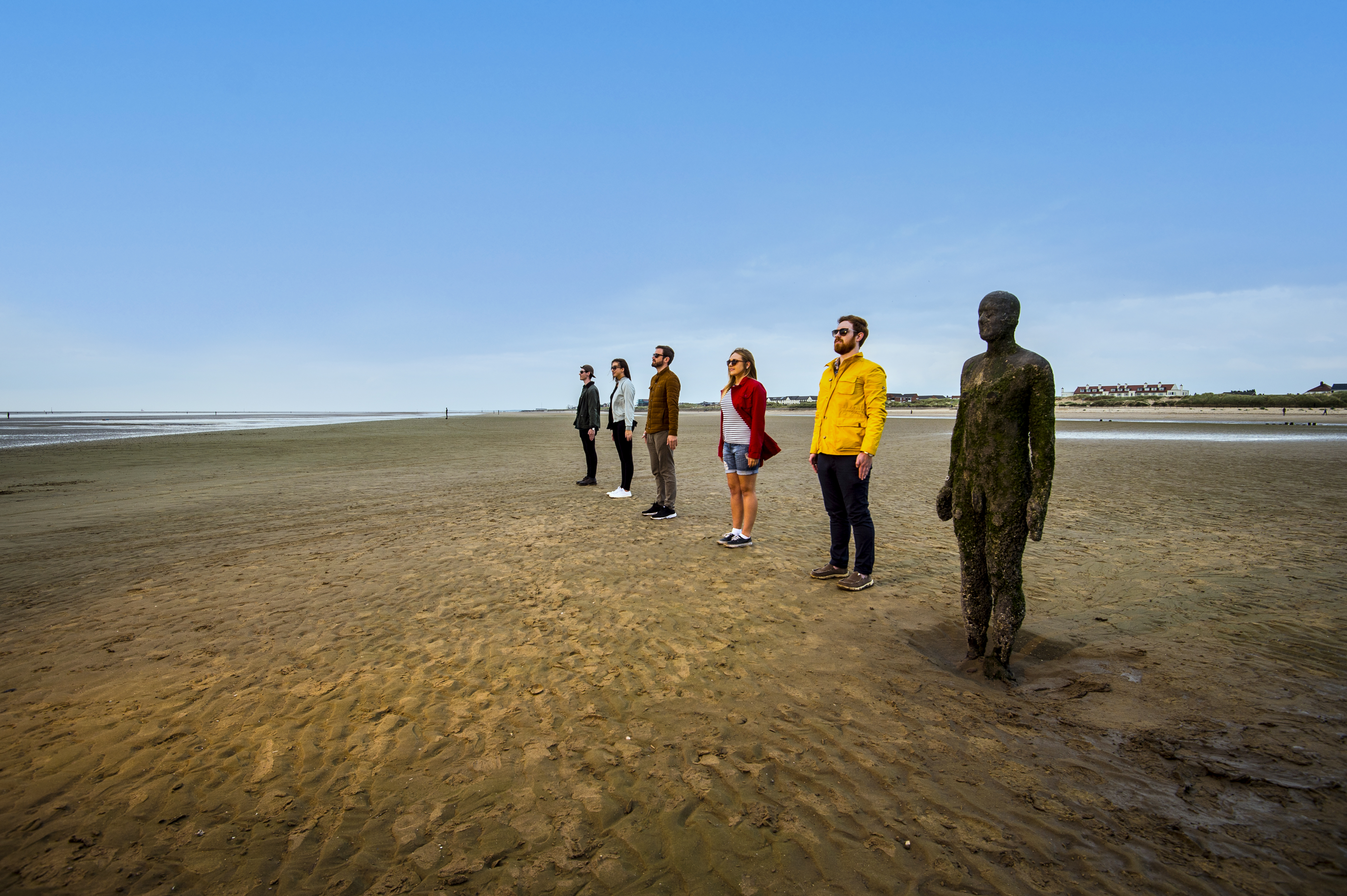 People standing in line beside a statue on the beach