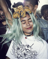 Chica con el pelo teñido, sonriendo, bailando con un grupo de personas