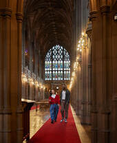 Two men chatting, exploring a large library.