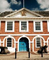 An outdoor shot of an historic building with two cannons outside