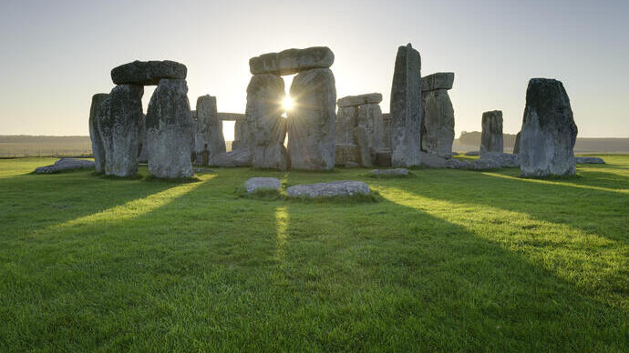 Large stone pillars arranged in circle on grass at sunset