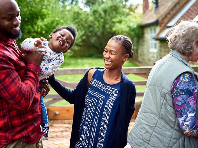 Family laughing in rural setting by a house