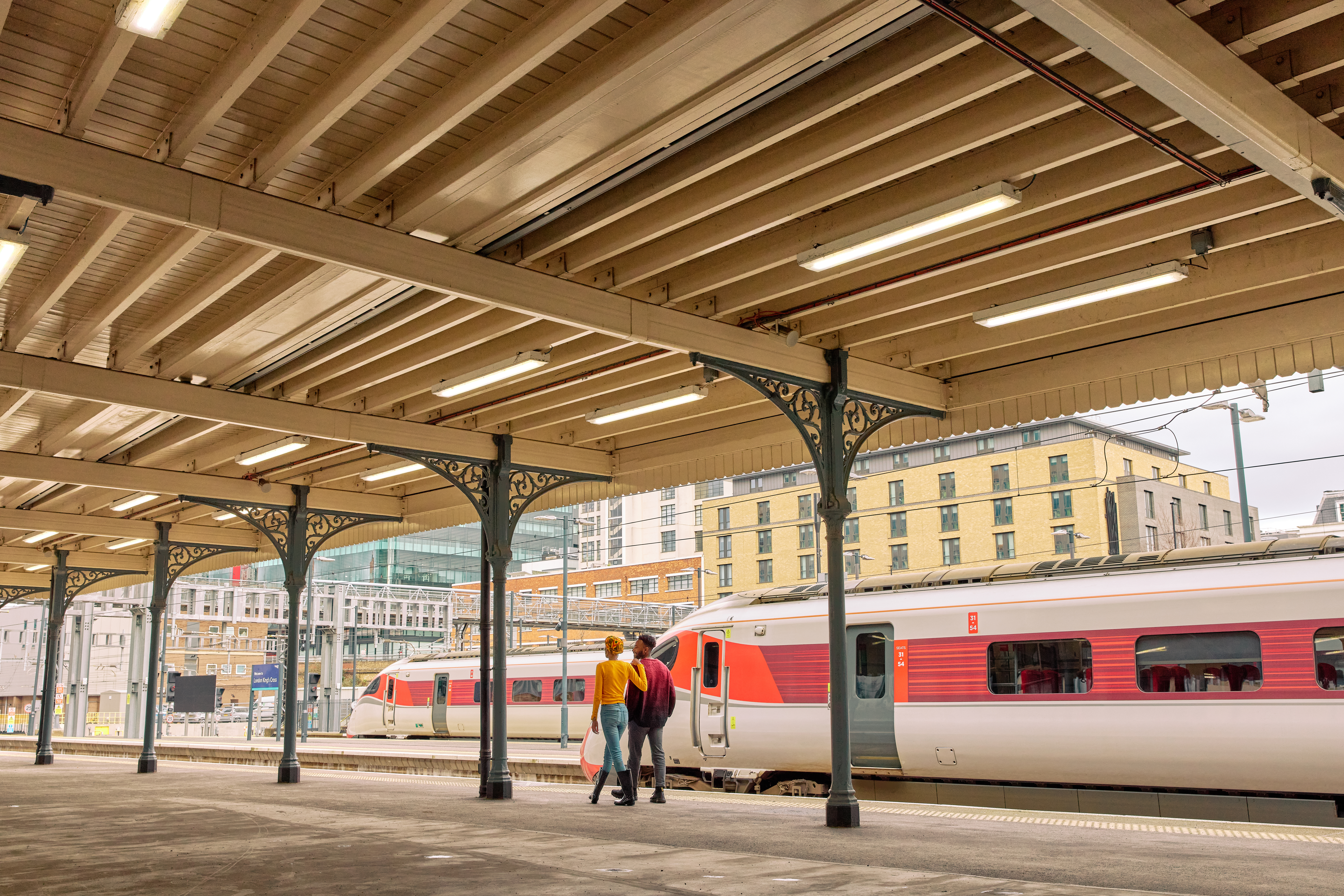 Man and woman walk along a train station platform